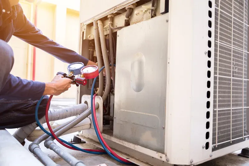 HVAC technician checking an outdoor air conditioning condenser unit during a service visit